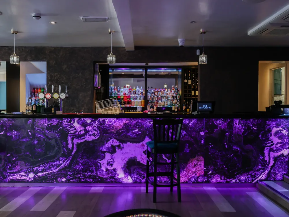 Nightclub in black and bronze textured plaster walls and backlit bar front